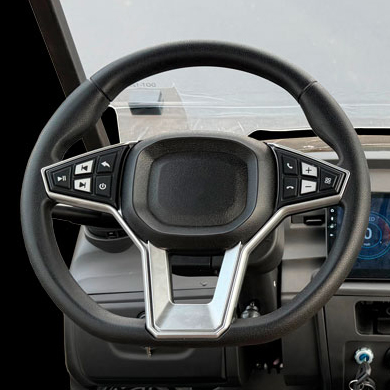 Steering wheel with integrated multi‑function controls and a metallic center, viewed from the driver’s perspective within a car interior.